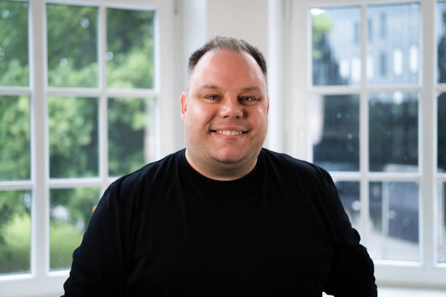 Björn Fiedler schaut freundlich in die Kamera. Er trägt kurze, dunkelblonde Haare und ein schwarzes Oberteil.