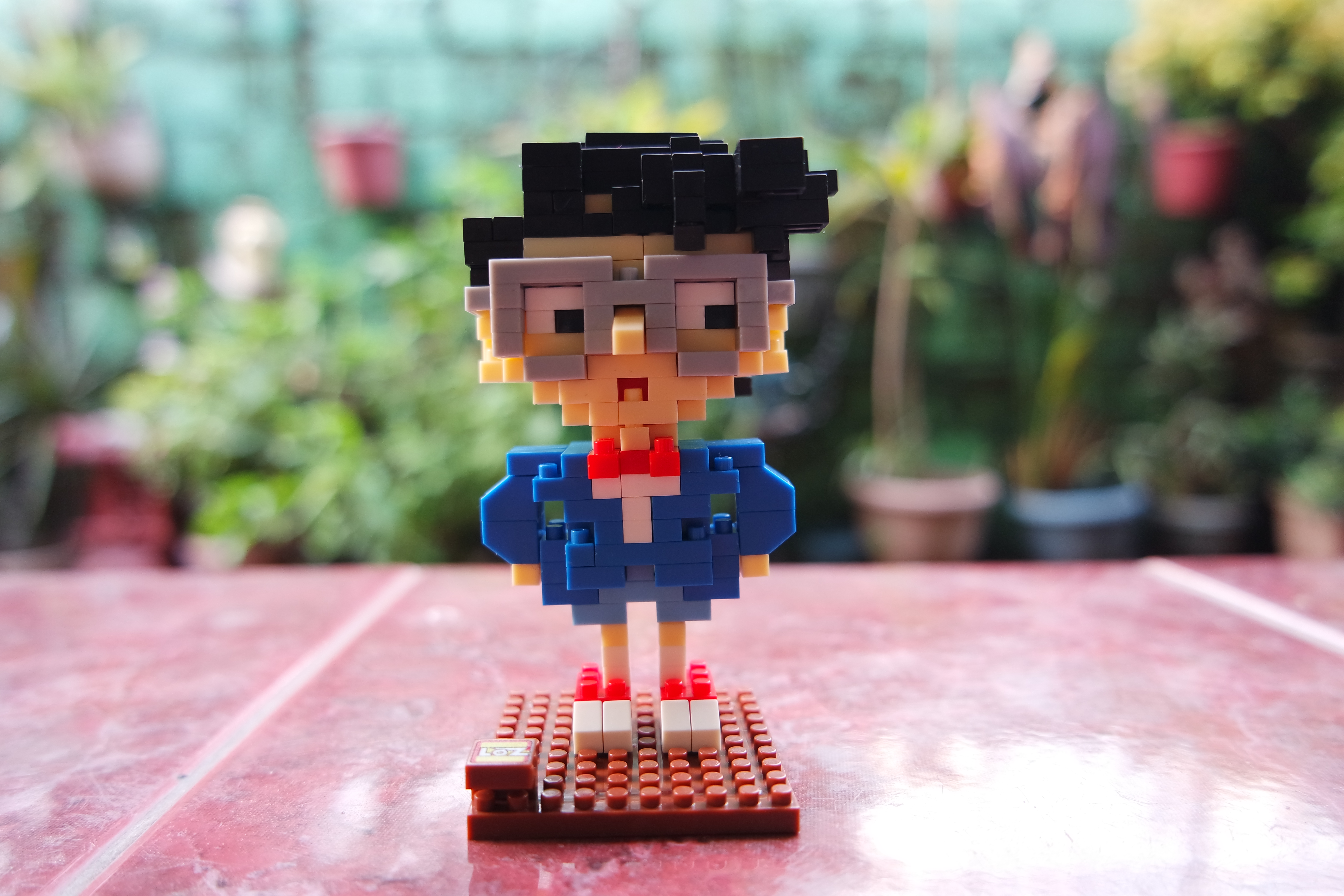 Eine Lego-Zaubererfigur mit blauem Umhang und Spitzhut steht vor einem aufgeschlagenen Buch und hält einen Zauberstab.